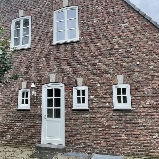 Historisches Backsteinhaus mit weißen Holzfenstern und Haustür