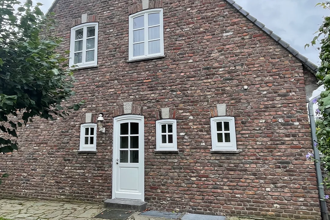 Historisches Backsteinhaus mit weißen Holzfenstern und Haustür